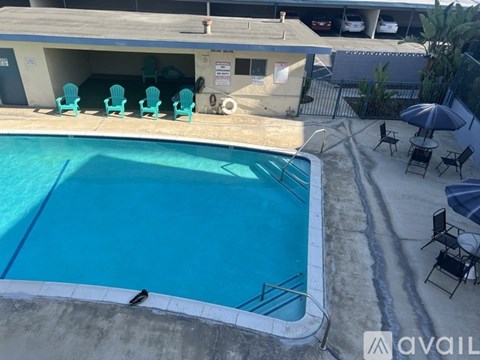 A pool with chairs around it and a building in the background.