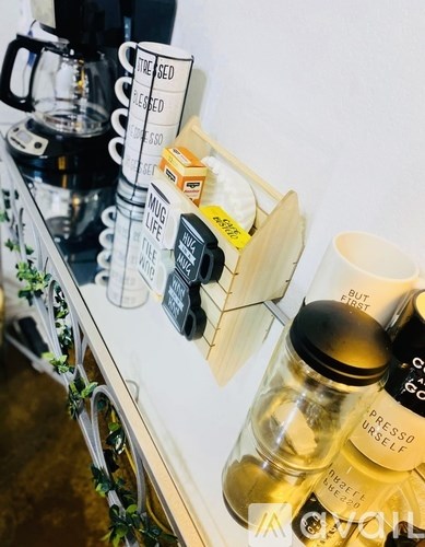 A shelf with various coffee products including a coffee maker, a jar of sugar, and a jar of creamer.