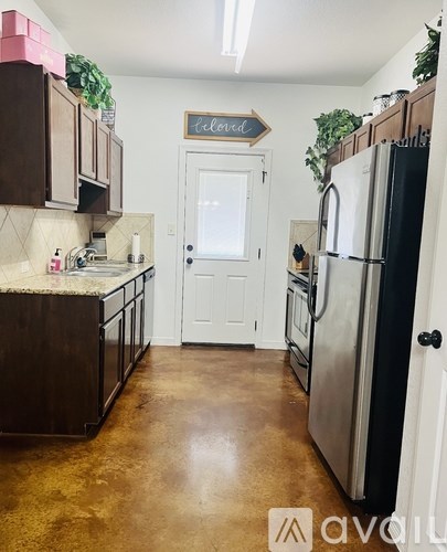 A kitchen with a white door and a black fridge.