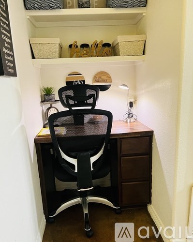 A black chair with a white back is in front of a desk with a computer.