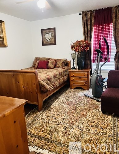 A room with a bed, a dresser, a chair, and a rug.