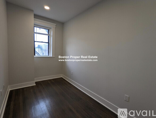 A room with wooden floors and a window showing a view of a building outside.
