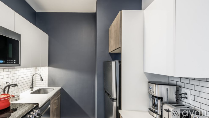 A modern kitchen with white cabinets and a black backsplash.