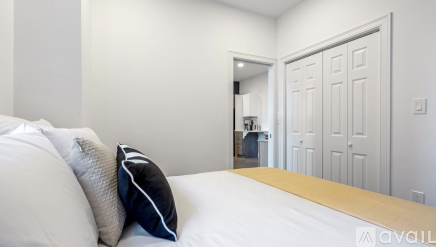 A bedroom with a bed, pillows, and a door.