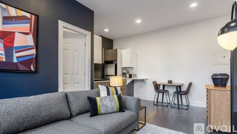 A grey couch with two pillows sits in a living room with a painting on the wall.