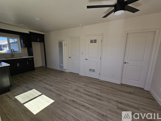 A room with a ceiling fan and wooden flooring.