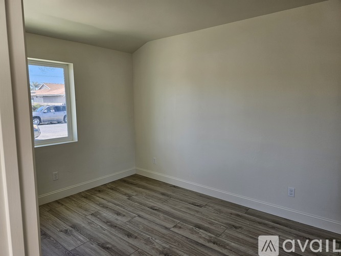 A room with wooden flooring and a window overlooking a street.