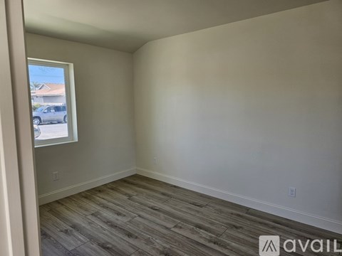A room with wooden flooring and a window overlooking a street.