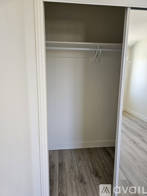 A white closet with a wooden floor and a white door.