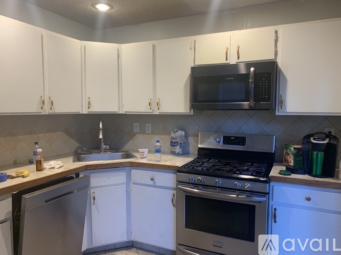 A kitchen with white cabinets and a black microwave above the stove.