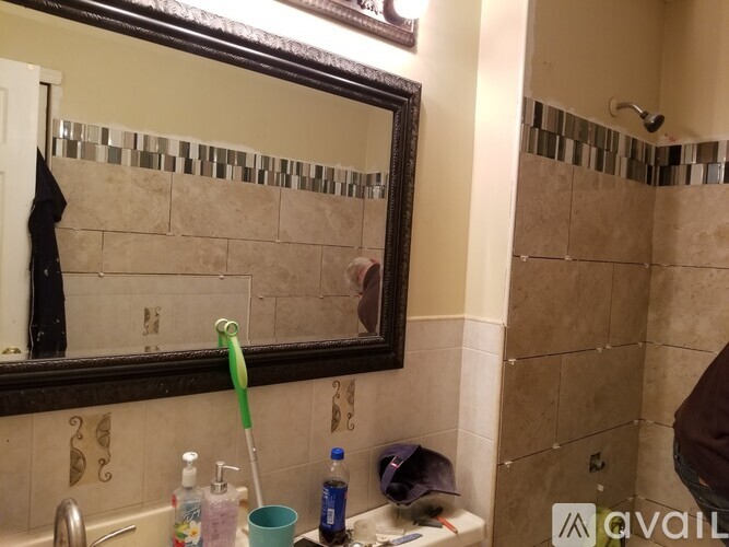 A bathroom with a mirror, sink, and shower.