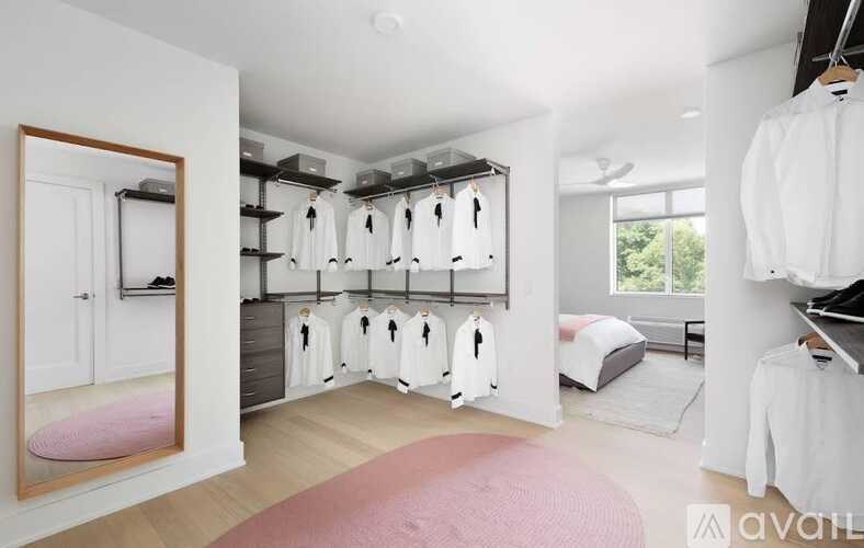 A bedroom with a pink rug and a row of hanging towels.