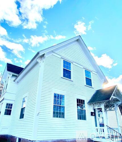 A white house with a black roof and a balcony.