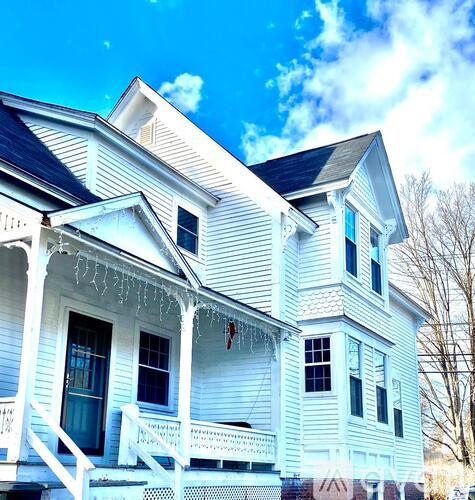 A white house with a dark roof and a balcony.
