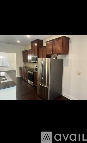 A kitchen with a stainless steel refrigerator and wooden cabinets.