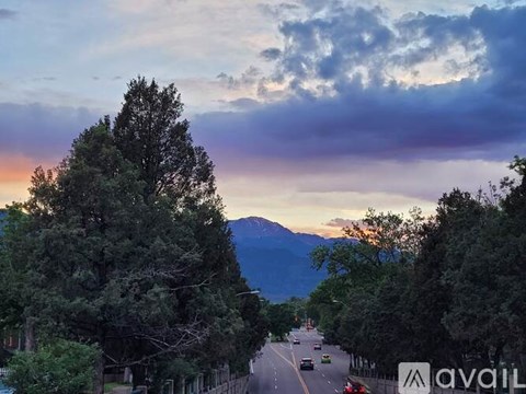A road with cars and trees on both sides under a cloudy sky.