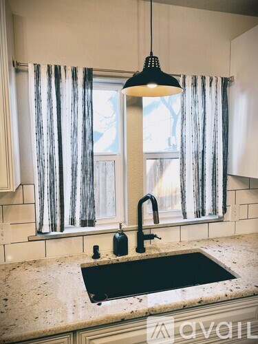 A kitchen with a sink and a window with curtains.