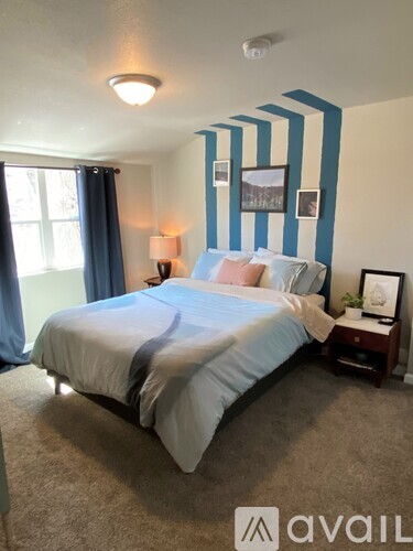 A bedroom with a bed, nightstand, and pictures on the wall.