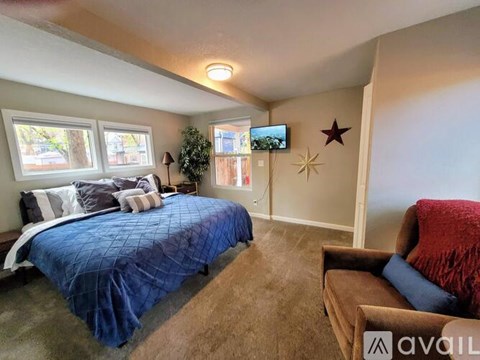 A bedroom with a blue bedspread and a brown armchair.