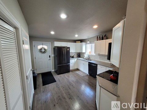 A kitchen with white cabinets and a black fridge.