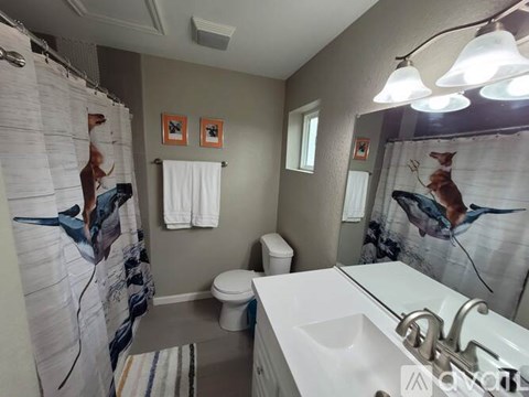 A bathroom with a white sink, toilet, and shower curtain.
