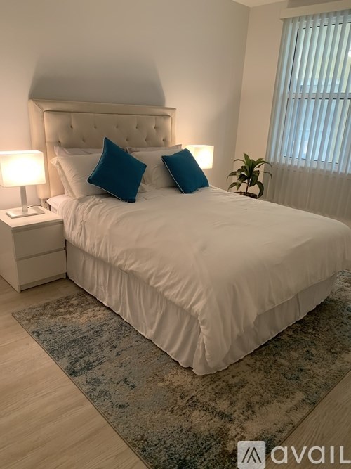 A bed with white sheets and two blue pillows is in the image.