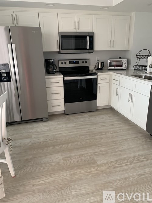 A kitchen with a refrigerator, microwave, oven, and cabinets.