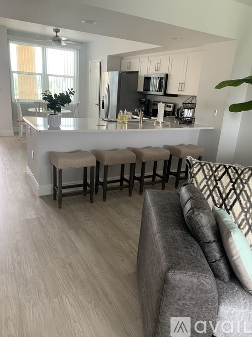 A kitchen with a bar stool and a grey couch.