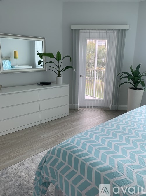 A bedroom with a bed, dresser, mirror, and plants.