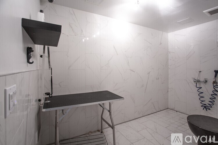 A bathroom with a black table and a shower with a hose.