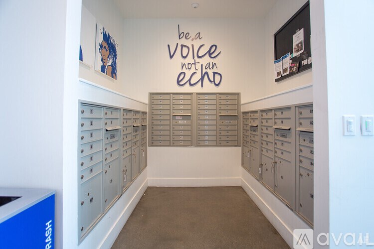 A wall with a sign that says "be a voice not an echo" is behind a row of mailboxes.