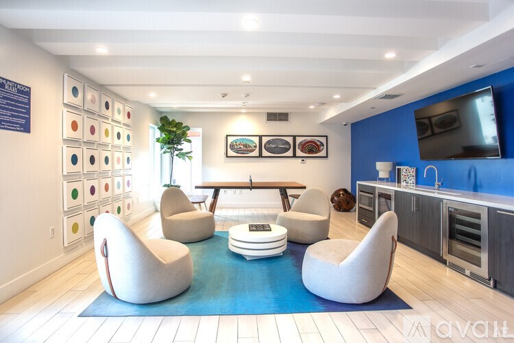 A modern living room with a blue rug and white chairs.