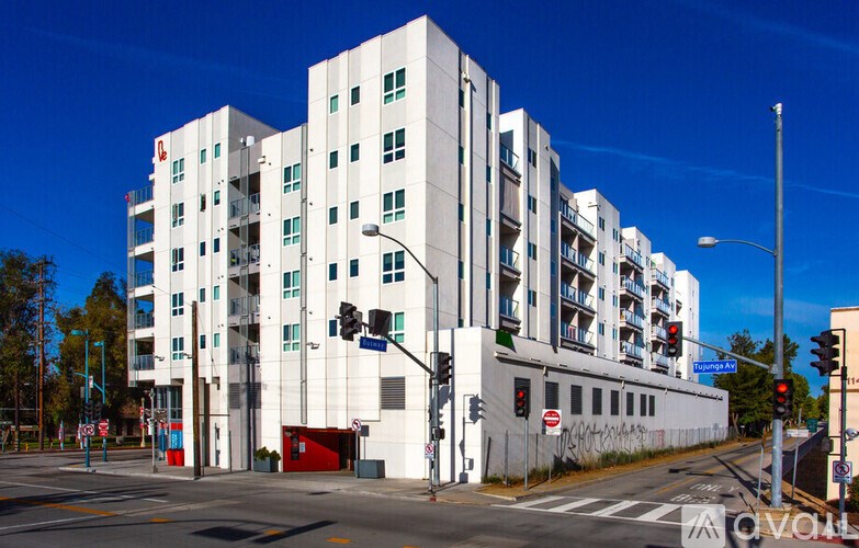 A white building with a red door is situated on a street corner.