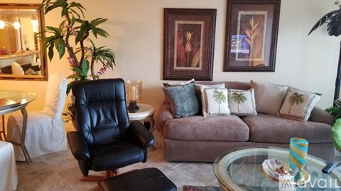 A living room with a black leather chair and a brown couch.