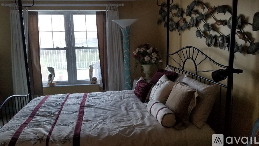 A bedroom with a bed, a window with a view, and a wall decoration.