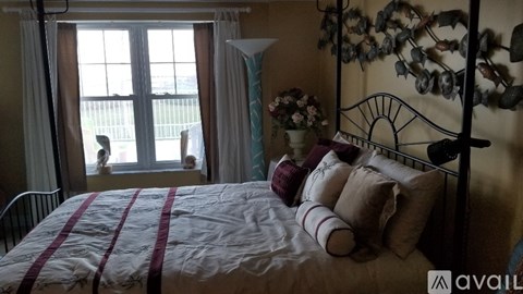 A bedroom with a bed, a window with a view, and a wall decoration.