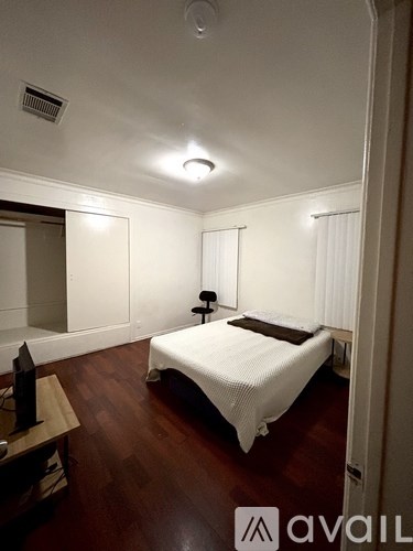 A bedroom with a bed, lamp, and wooden floors.