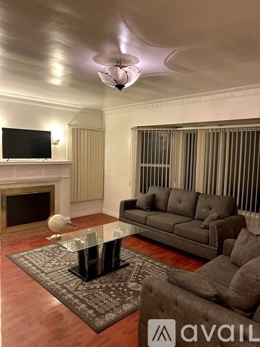 A living room with a grey couch, a glass coffee table, and a television.