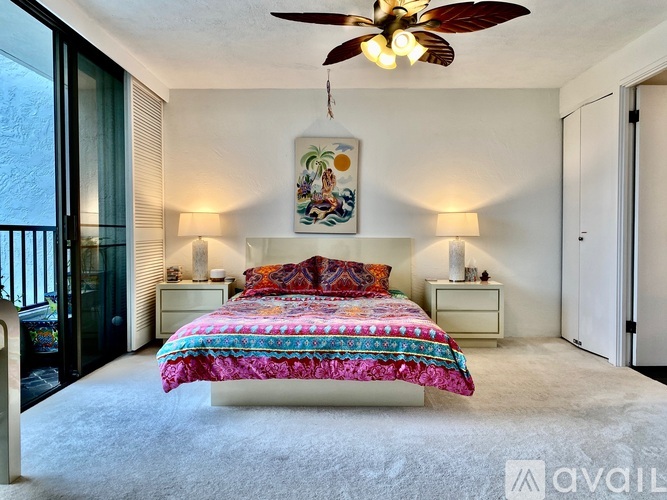 A bedroom with a bed, two lamps, and a ceiling fan.