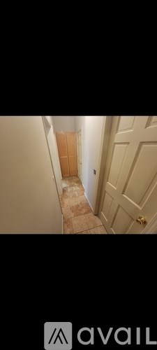 A hallway with a tiled floor and a wooden door.