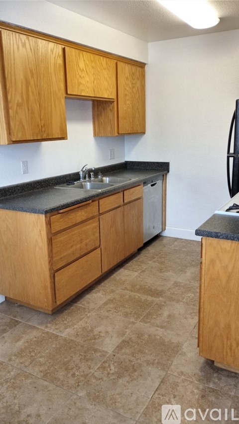 A kitchen with wooden cabinets and a black countertop.