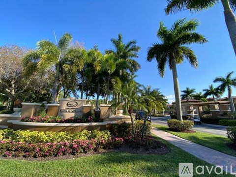 A sunny day at a park with palm trees and a sign that says "AVAIL".