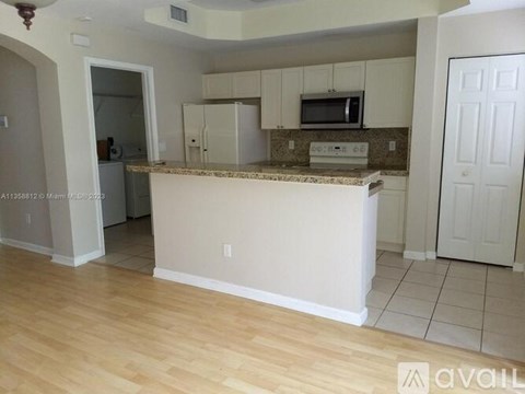 A kitchen with white cabinets and a granite countertop.