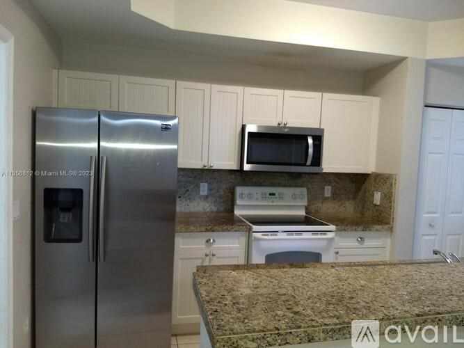 A kitchen with a granite countertop and stainless steel appliances.