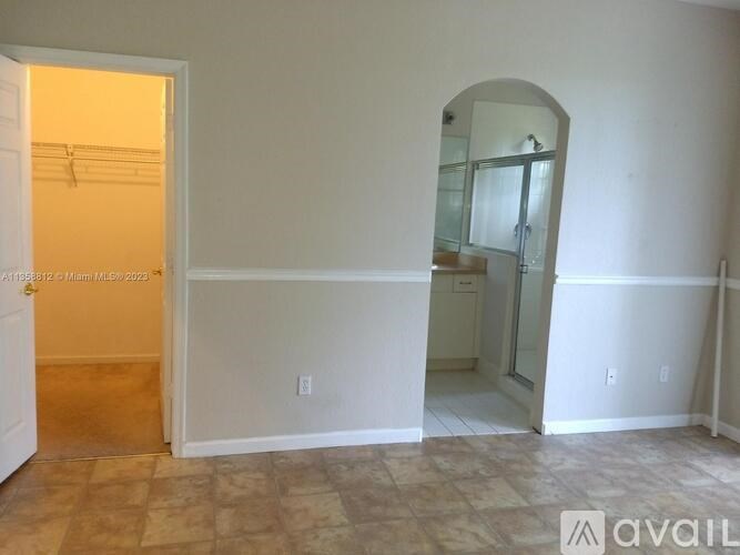 A room with a doorway leading to another room and a mirror on the wall.