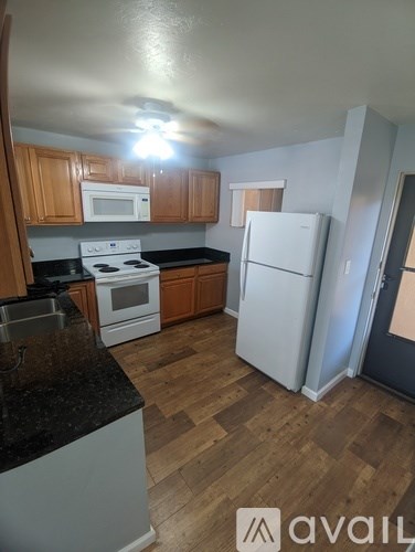 A kitchen with a white refrigerator and a black counter top.