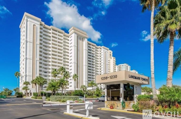 The image shows a tall white hotel named Landmark Towers with a blue sky and palm trees in the background.