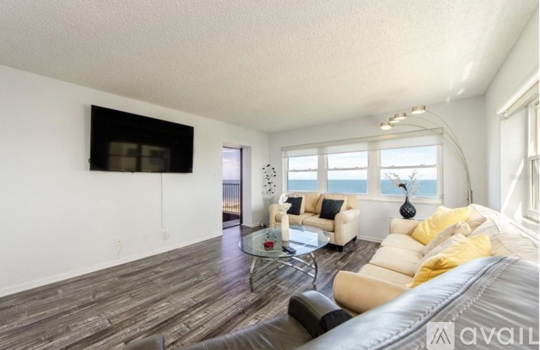 A living room with a large couch and a flat screen TV mounted on the wall.
