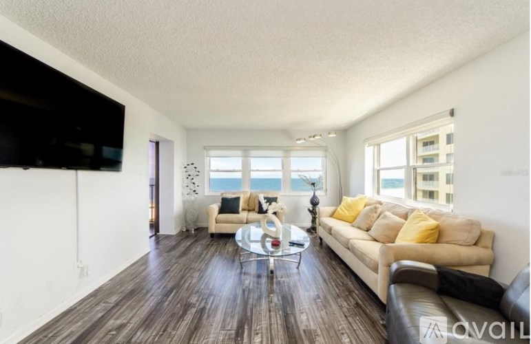A living room with a couch, coffee table, and a flat screen TV mounted on the wall.