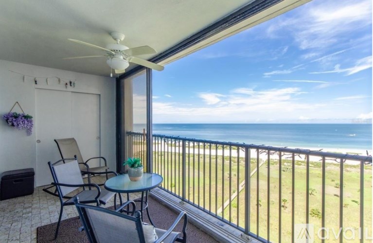 A balcony with a table and chairs overlooking the beach.